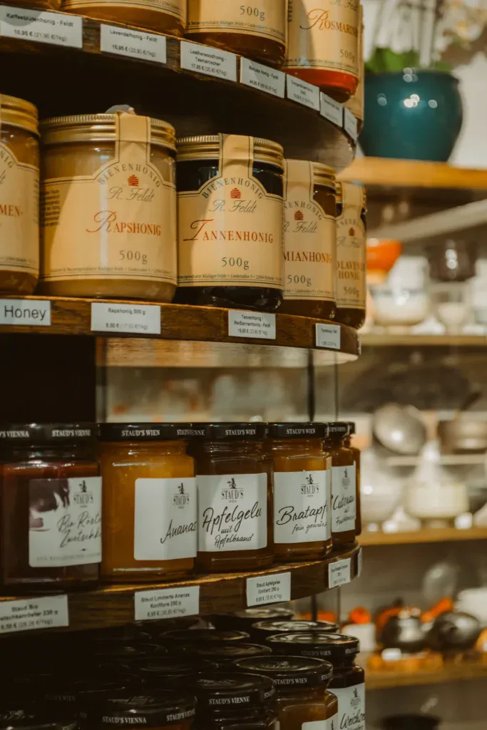 Close-up of honey jars on shelves, showcasing various flavors and labels.