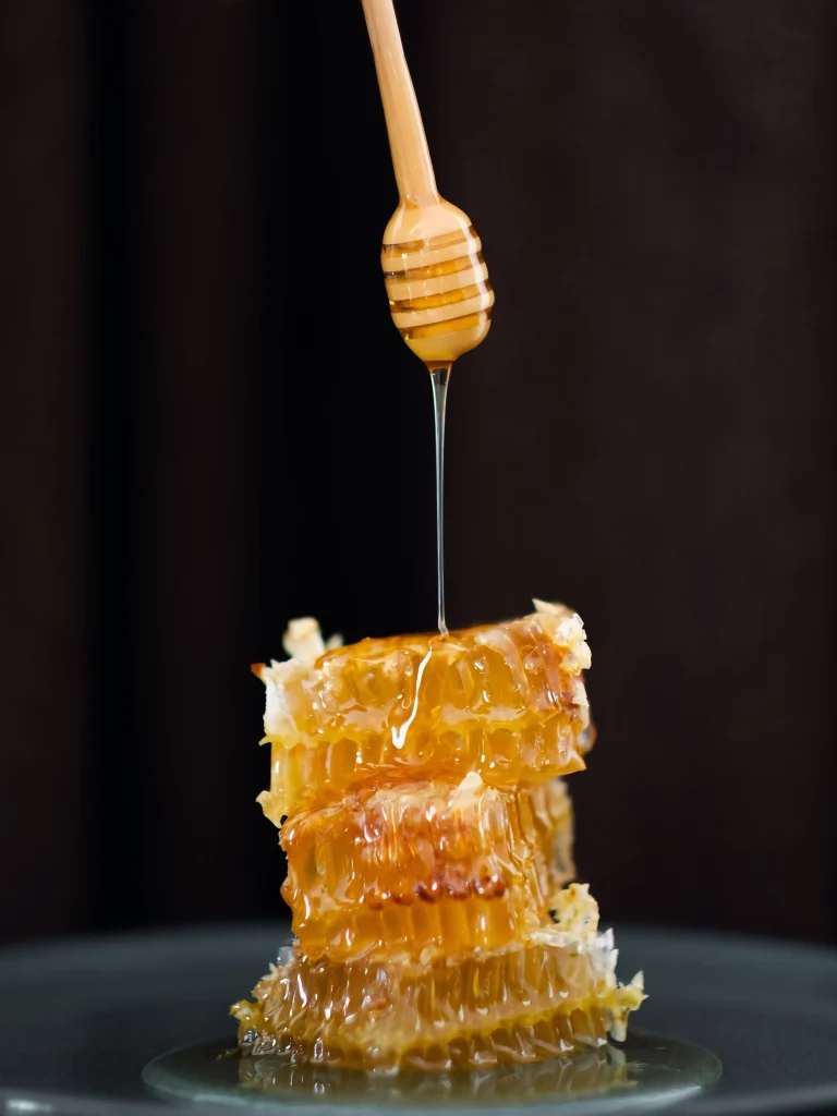 Delicious manuka honey dripping from a dipper onto honeycomb